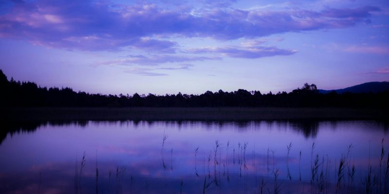 A serene landscape with a calm lake reflecting the sky, symbolizing peace and philosophy.